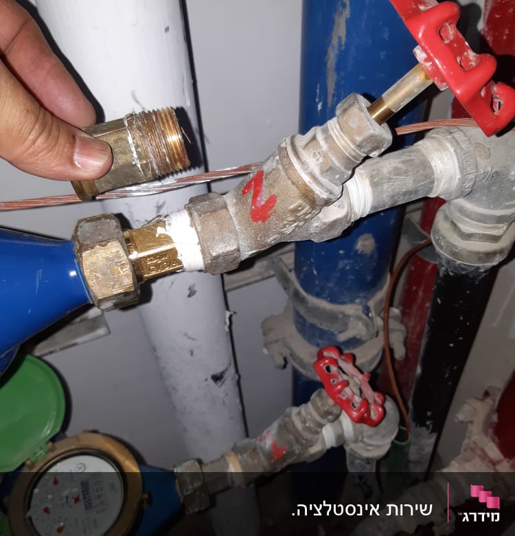 יד מחזיקה מחבר פליז ליד ברזים וצינורות